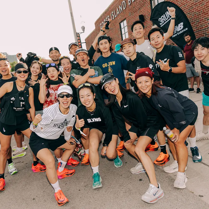 A run crew cheering for a group photo on a street