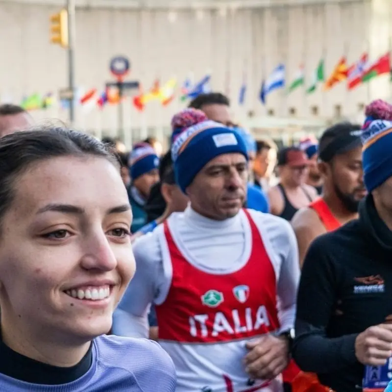 Runners packed into a start corral under a row of flags