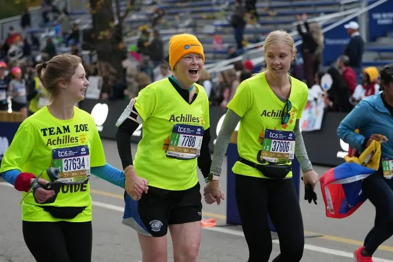 Runners in bright yellow Achilles shirts on the marathon course