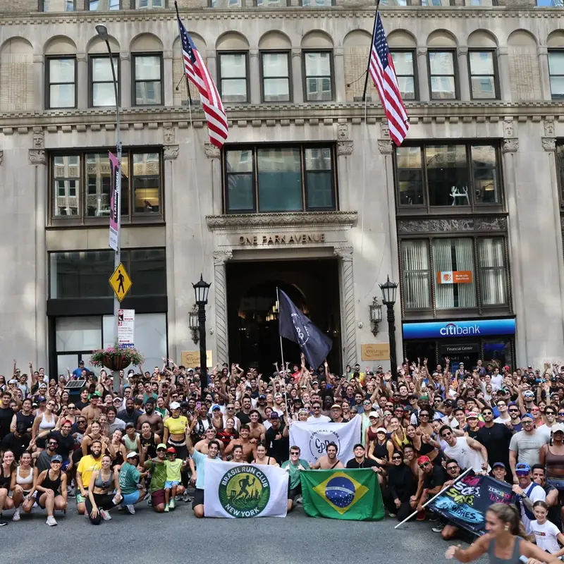 A big run club with flags filling a Park Avenue sidewalk