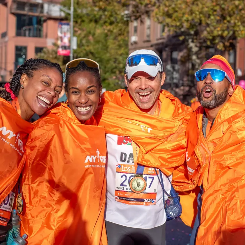 Grinning finishers in orange ponchos with their medals