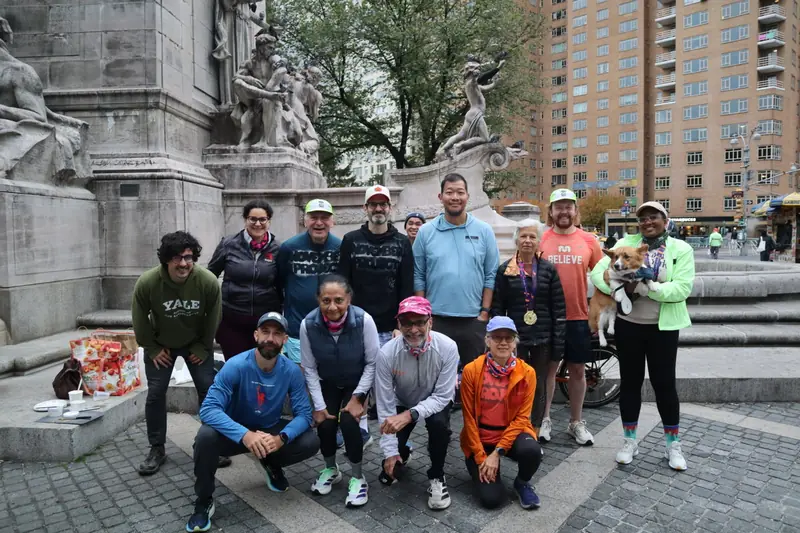 A group posing by a monument's fountain at Columbus Circle