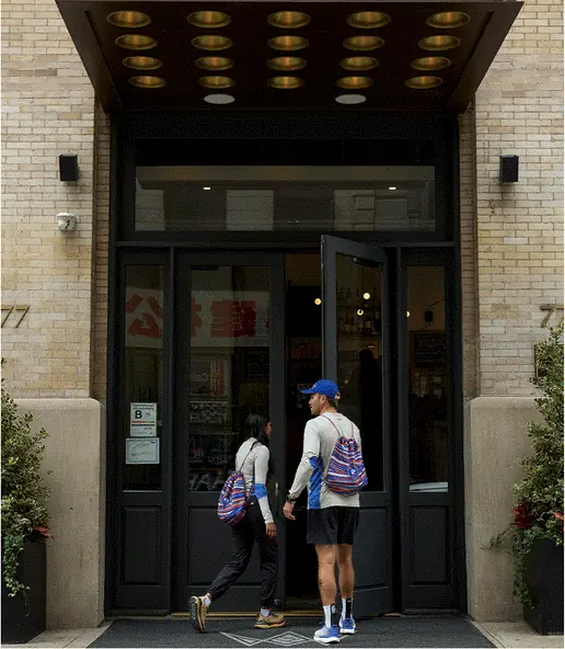 Two runners walking into a hotel's lit doorway