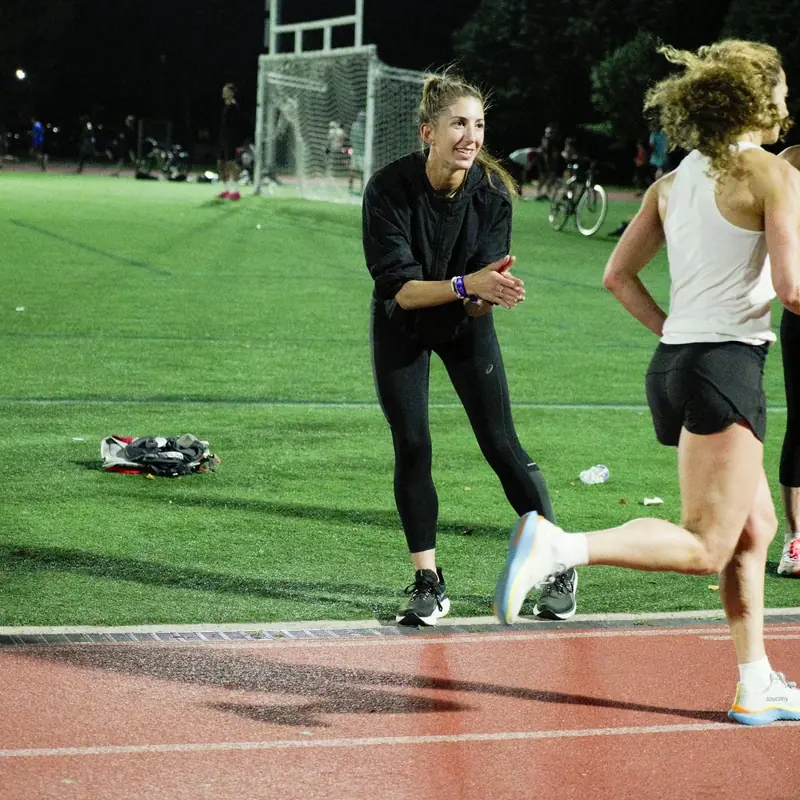 A coach high-fiving a runner on a track at night