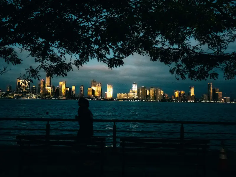 A runner silhouetted by the river at dusk, the skyline lit across the water