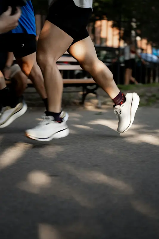 Runners' legs and shoes on a sunlit park path