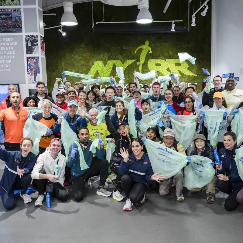 A group of ploggers with bags posing in front of a runners' club wall