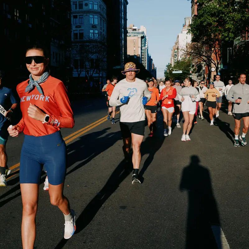 A group run down a sunny Manhattan avenue, towers behind