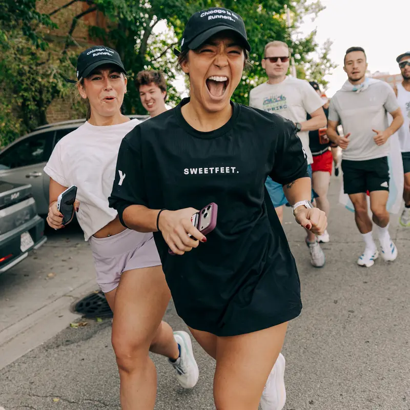 A runner laughing on a group run through a neighborhood