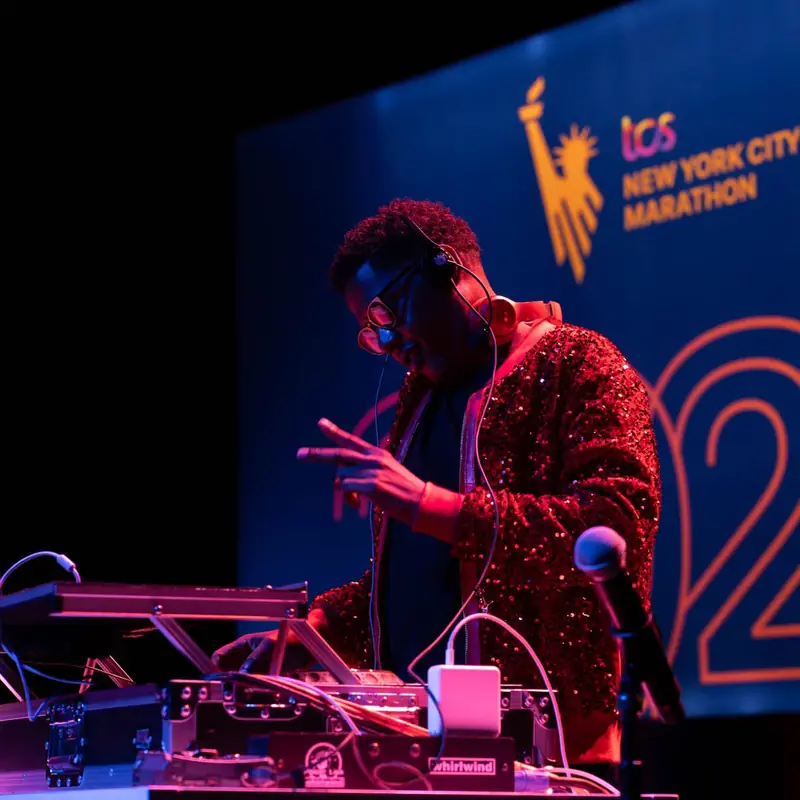 A DJ in a sequined jacket playing on a stage