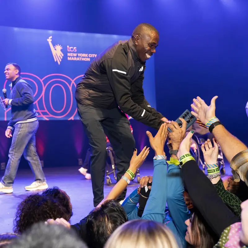 A speaker on stage high-fiving a crowd of fans